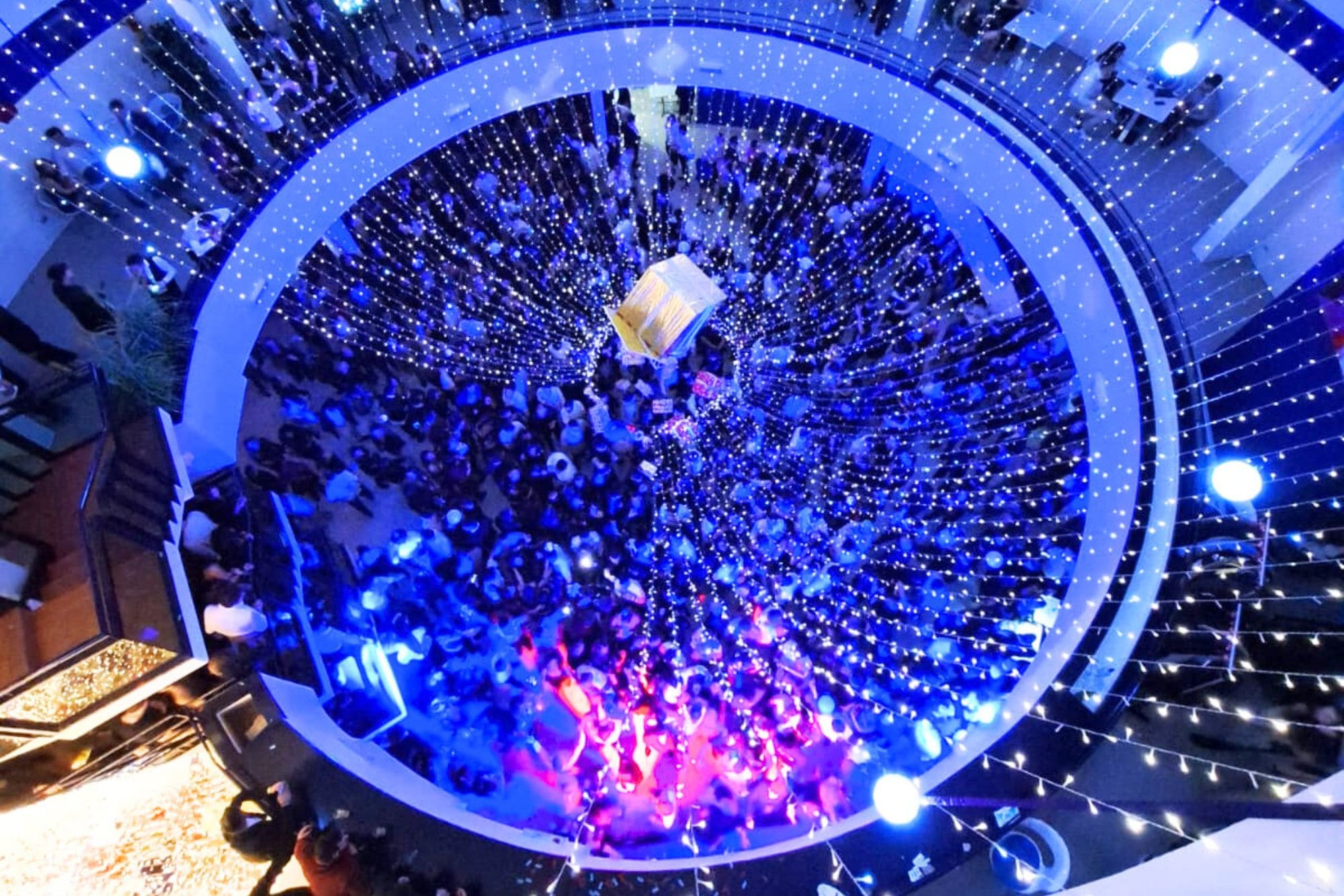 Brindisi di Capodanno al Cala Corvino Resort, vista aerea del ristorante centrale illuminato a festa con luci blu e dorate.