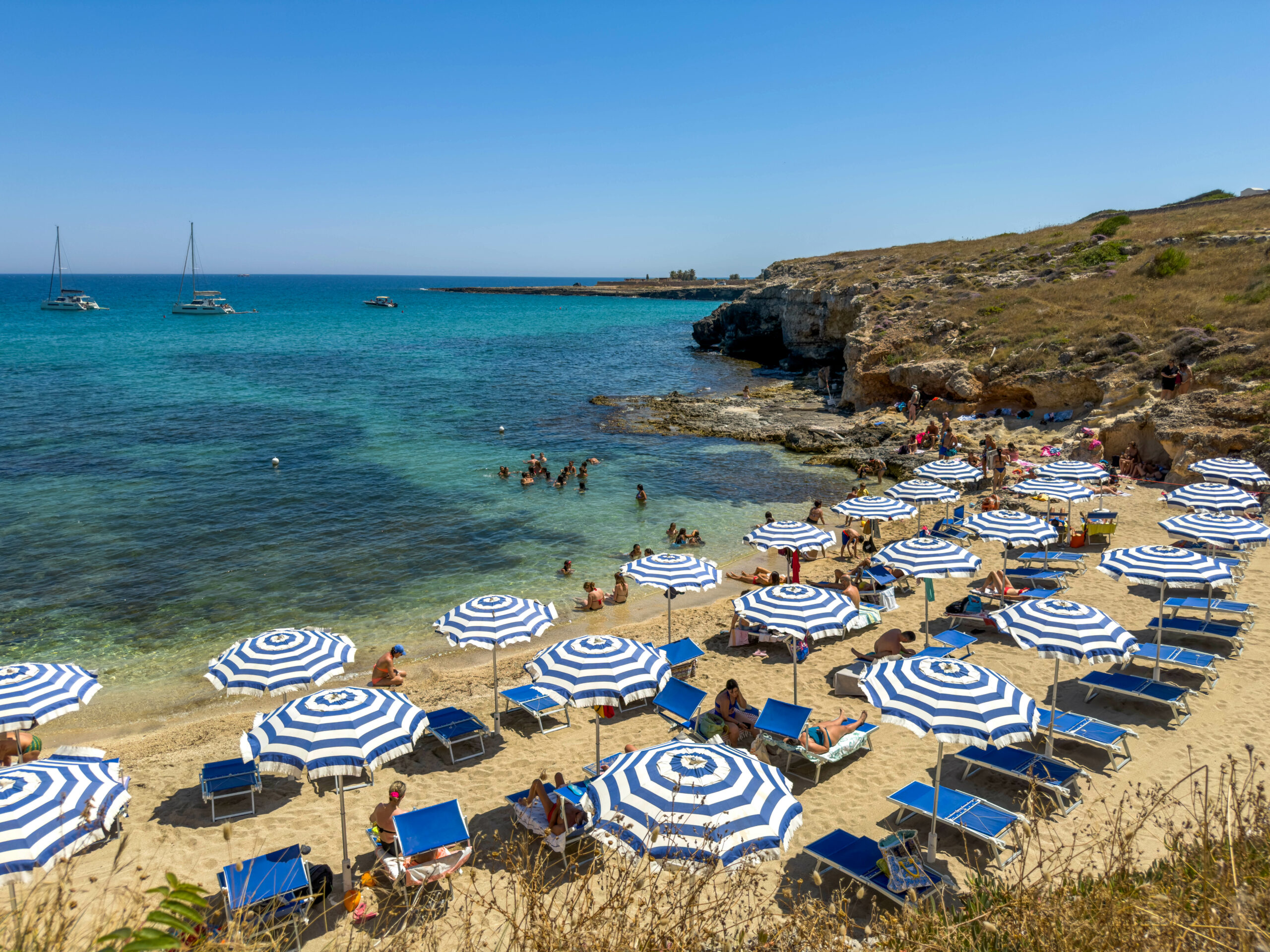 Spiaggia di Cala Corvino con ombrelloni e lettini, mare cristallino e caletta naturale a Monopoli